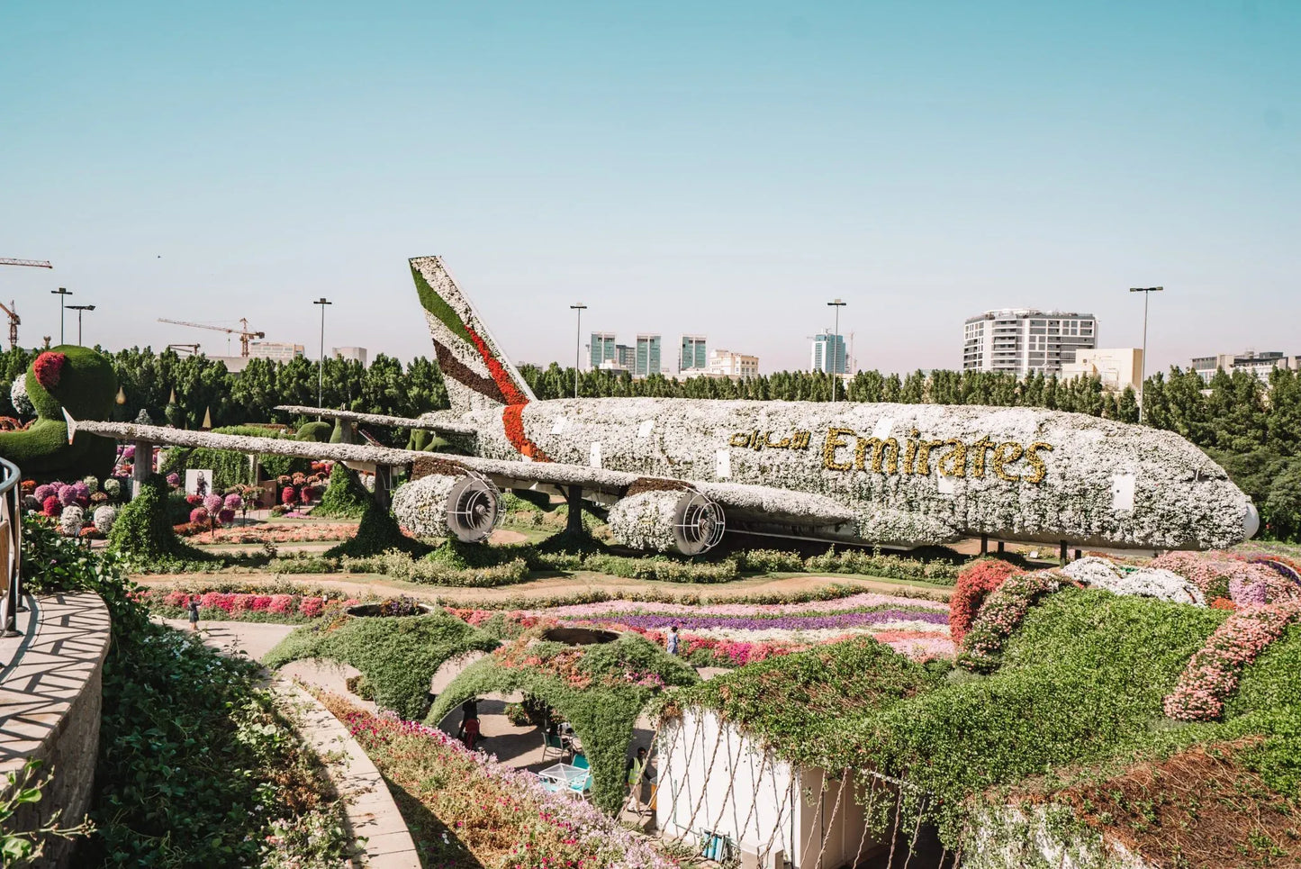 An Emirates airplane in a lush garden setting.